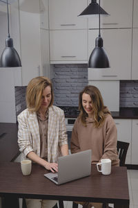 Portrait of woman using digital tablet while sitting at table