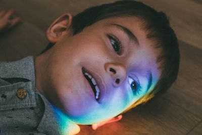 High angle view of boy lying by rainbow light falling on hardwood floor