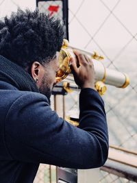 Side view of man looking through coin-operated binoculars