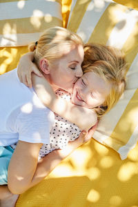 Happy girl and mother hugging and kissing on a blanket