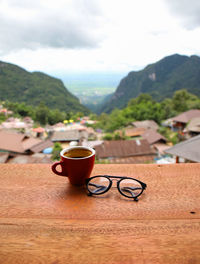 Close-up of coffee cup on table against mountains