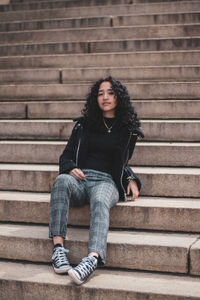 Full length of young woman sitting on staircase