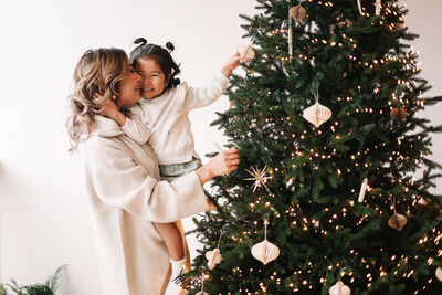 Asian multiracial mom and little daughter celebrate christmas holiday in decorated house