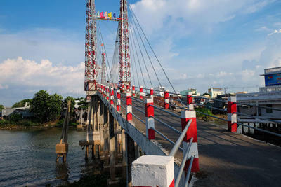 30m long bridge over a tributary to the mekong river. red and white spires. 