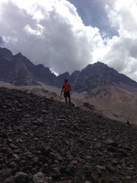 Man standing on mountain against cloudy sky