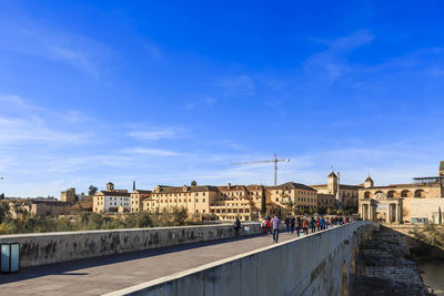 People on historic building against blue sky