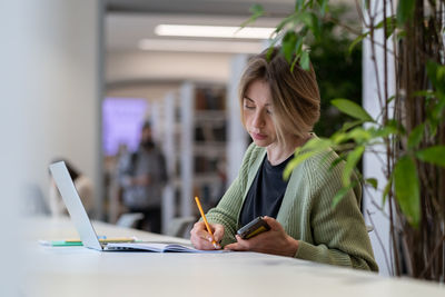 Academic career. female university professor taking notes in day planner while sitting in library