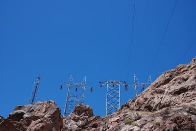 Low angle view of power lines against clear blue sky