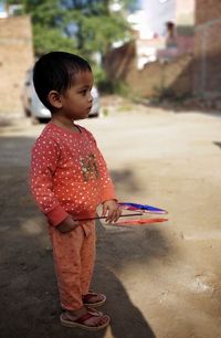 Full length of girl with pinwheel standing on footpath