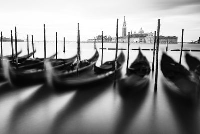 Gondolas moored by wooden post at grand canal against sky