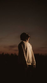 Rear view of man standing on field against sky during sunset