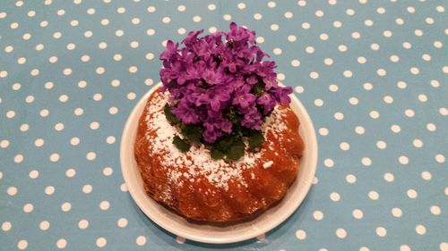 High angle view of homemade cake with purple flowers on table