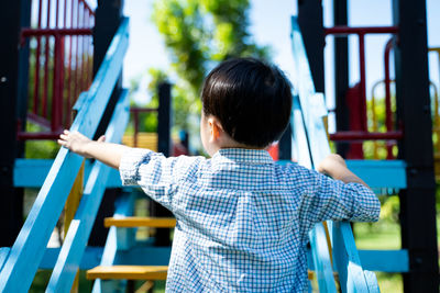 Rear view of boy walking on metal structure