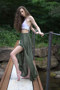 Full length portrait of young woman standing in footbridge