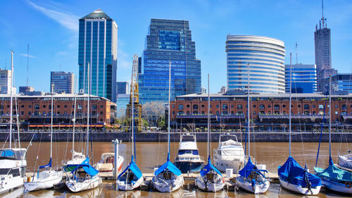 Boats moored in canal against modern buildings in city