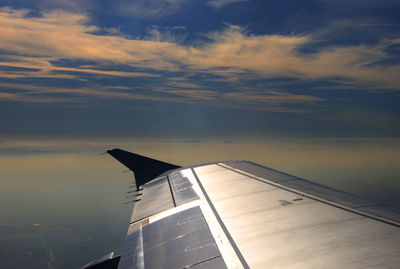 Close-up of airplane wing over sea against sky
