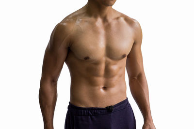 Midsection of shirtless muscular man standing against white background