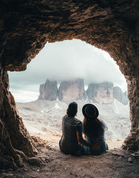 Rear view of people sitting on rock looking at view