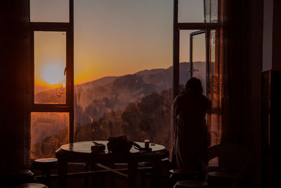 Rear view of silhouette woman standing by window