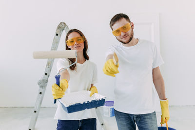 Happy smiling married couple engaged in renovation repair in the room of the house preparing to move