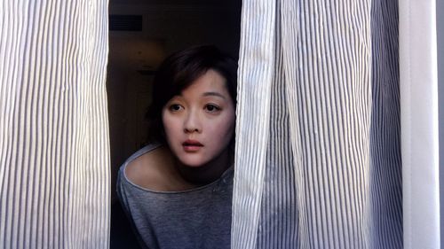 Close-up of woman looking through window