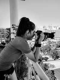 Side view of woman photographing against sky