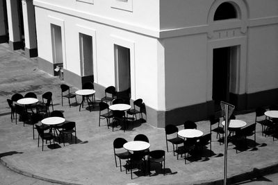 High angle view of chairs and tables arranged at sidewalk in city