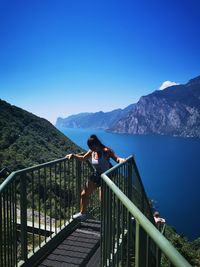 Full length of woman standing on steps against lake and mountain