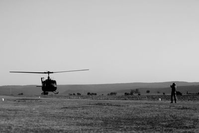 Airplane flying over field against clear sky