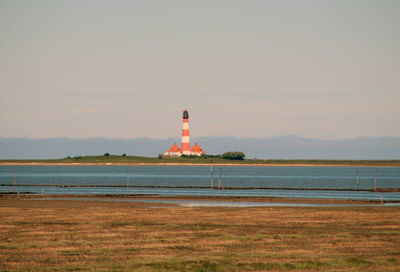 Scenic view of lighthouse next to grassy area against clear sky