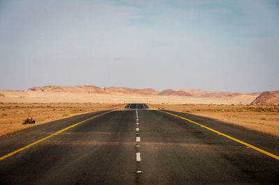 Road passing through desert against sky