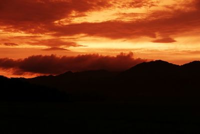 Silhouette of mountain range against cloudy sky