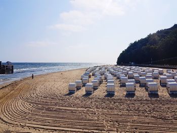 Hooded chairs on beach against sky