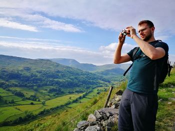 Young man standing on mountain against sky
