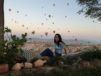 Woman sitting on rock against sky