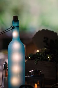 Close-up of illuminated bottle with christmas lights indoors