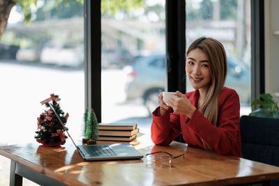 Young woman using mobile phone while sitting on table