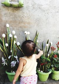 Rear view of girl by potted plants