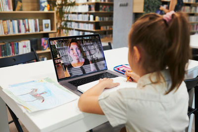 Student litttle girl having video class remotely with her teacher on laptop. back to school