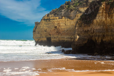 Rock formation on beach against sky