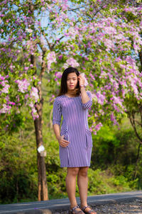 Young woman standing on purple flowering tree
