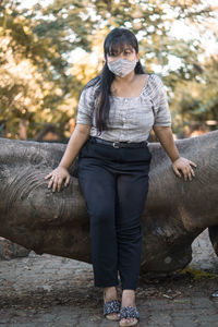 Full length portrait of woman standing against tree
