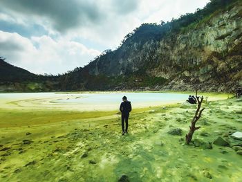 Rear view of man standing on land against sky