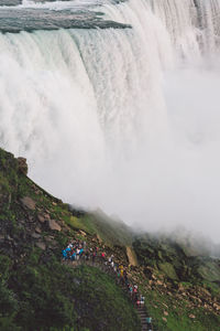 People by waterfall against sky