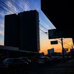 Cars in city against sky during sunset