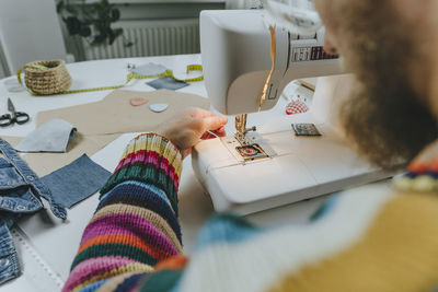 Fashion designer adjusting thread in sewing machine