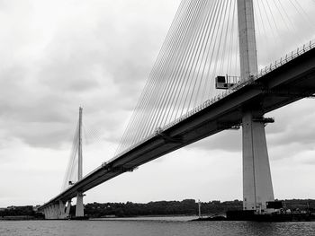 Low angle view of suspension bridge against cloudy sky