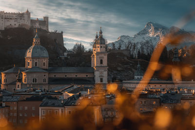 Buildings in city against cloudy sky