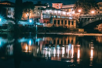 Illuminated buildings by lake at night