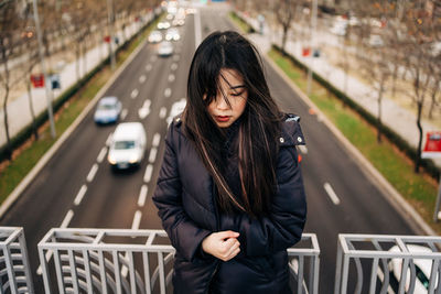 Young woman standing on railing in city